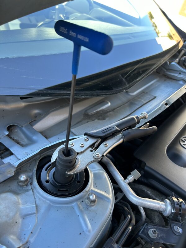 removing the OEM strut tower bolt using hex key and vise grip pliers